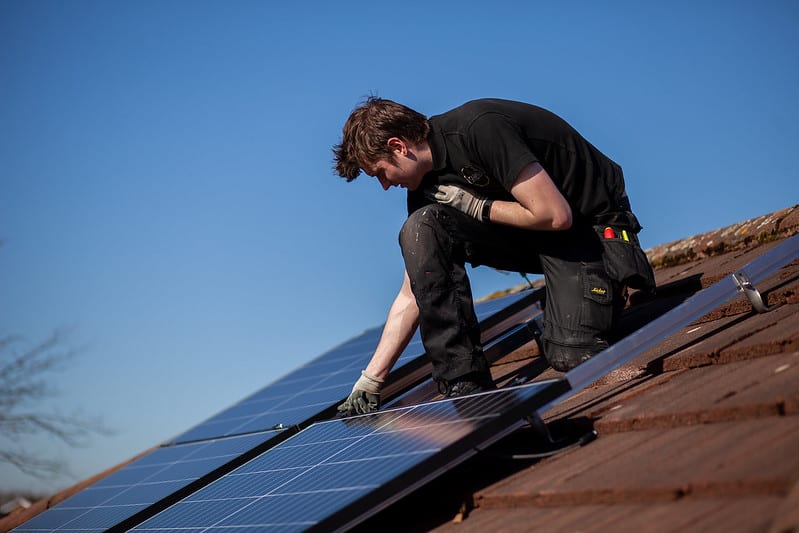 Man on roof fitting a solar panel