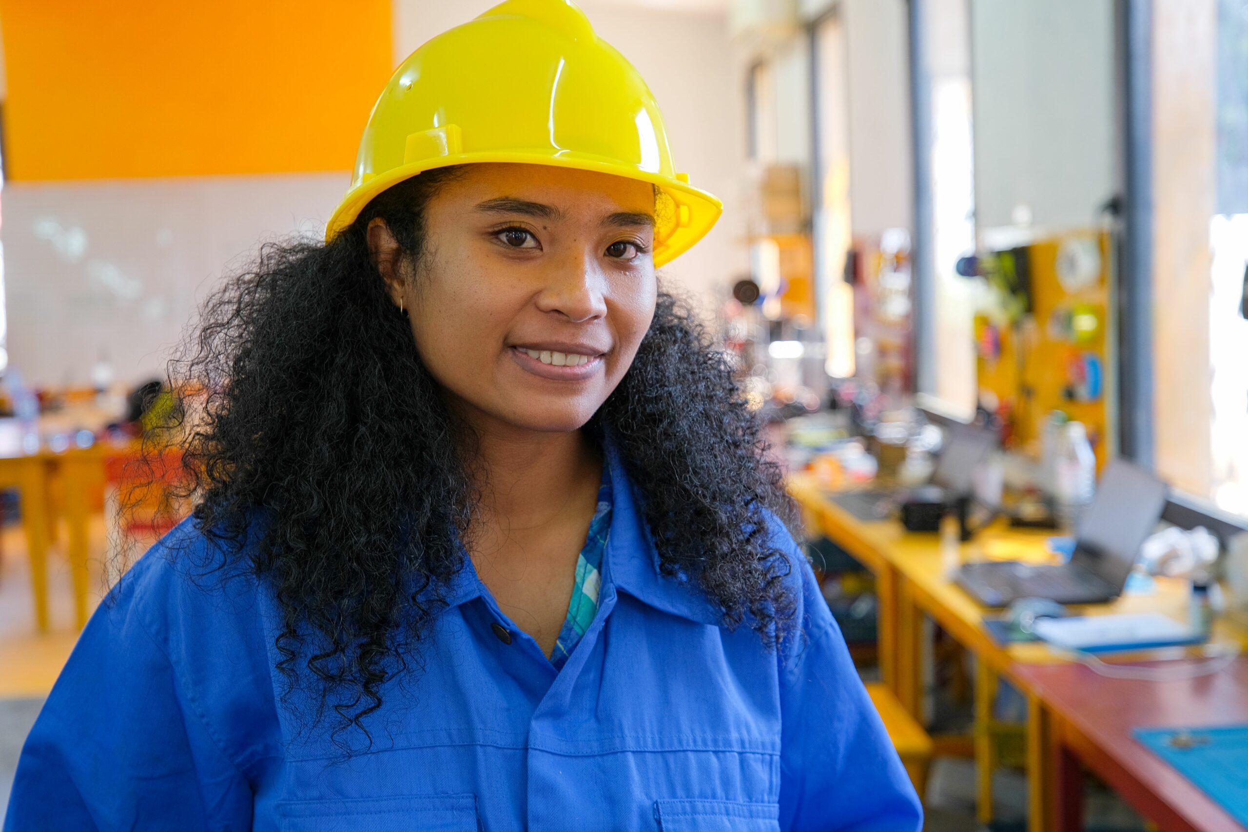 A traineee at Energy Generation with a yellow helmet on smiling at the camera