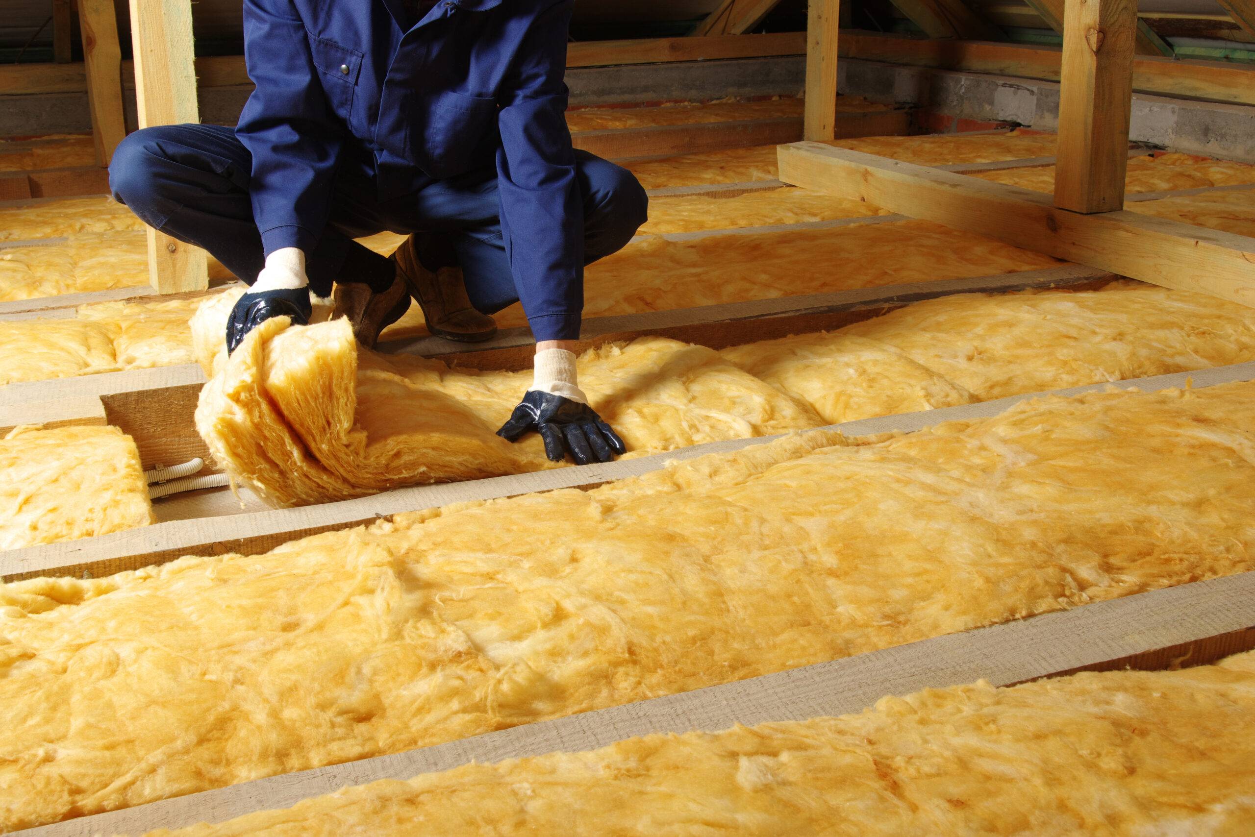 A man in work gloves installing thermal insulation.