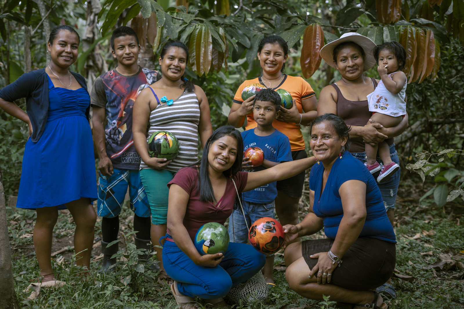 A group of 9 people standing and smiling at the camera holding painted round balls