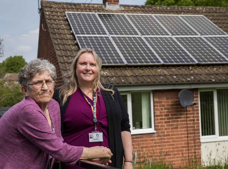 Two women standing infront of a house with solar panels on.