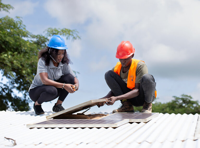 Patapia staff; Rehema and Musobozi Pius (26), an electrician, inspecting solar pannels installed for some of their clients in Kyempango village, Kamwenge district - Uganda