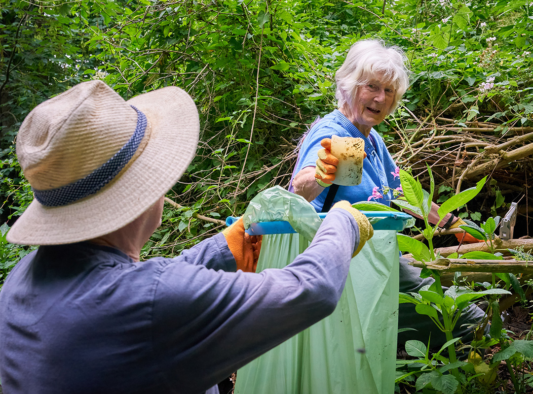 Woman cleaning rubbish from the side of the river and putting it in a rubbish bag
