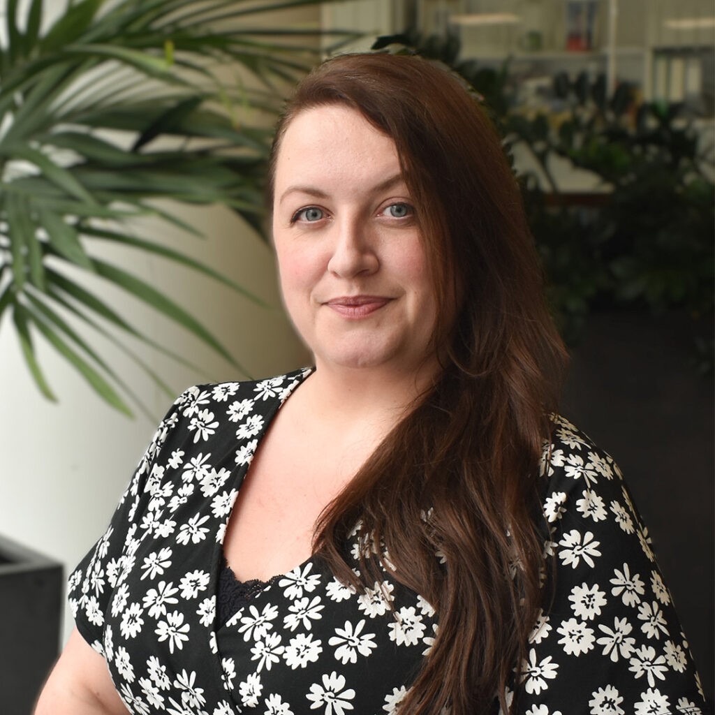 Woman wearing a black top with white flowers on smiling at camera