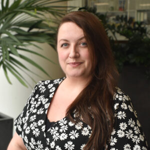 Woman wearing a black top with white flowers on smiling at camera