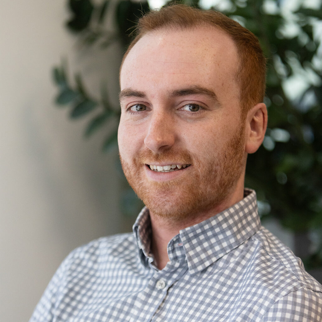 Man wearing a blue checked shirt smiling at camera