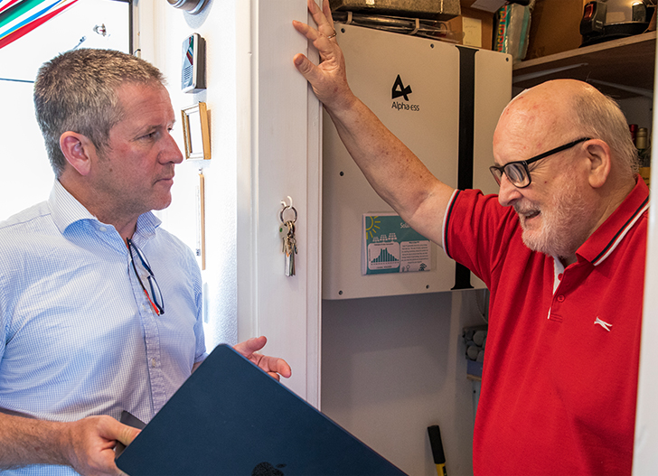 A council home owner stands, with a member of Energise Barnsley, beside his newly installed electric boiler that is powered by solar panels.