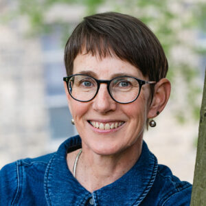 Woman with short hair and glasses smiling at camera