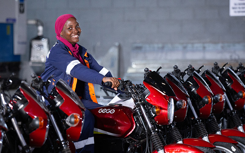 A worked at Gogo Electric is sitting on one of their electric motorbikes which are greening travel in Uganda.