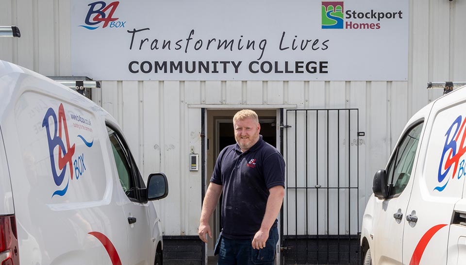 B4BOX, who train apprentices in retrofitting housing, pose in front of their warehouse and vans.
