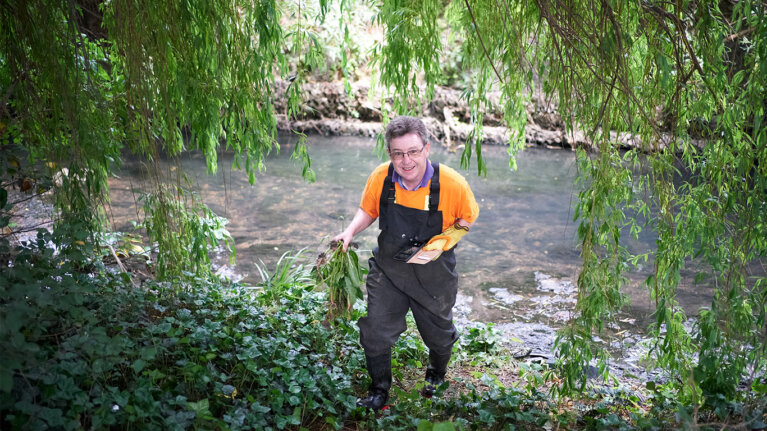 Man holding vegetation by a river