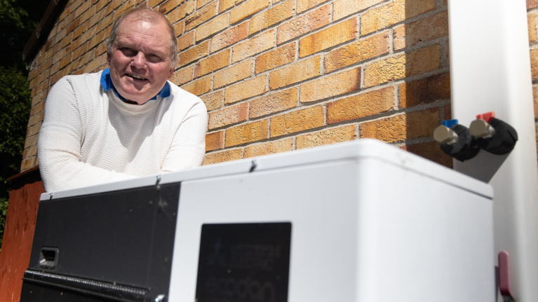 A resident smiling next to a heat pump
