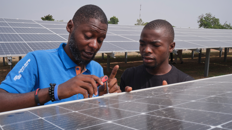 Close up of two male installers screwing into a solar panel