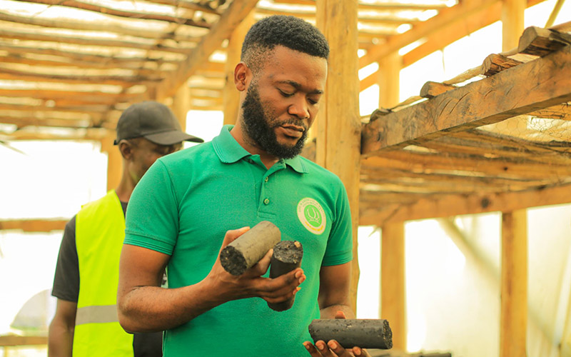 A member of Live in Green is holding some of their environmentally-friendly compressed briquettes.