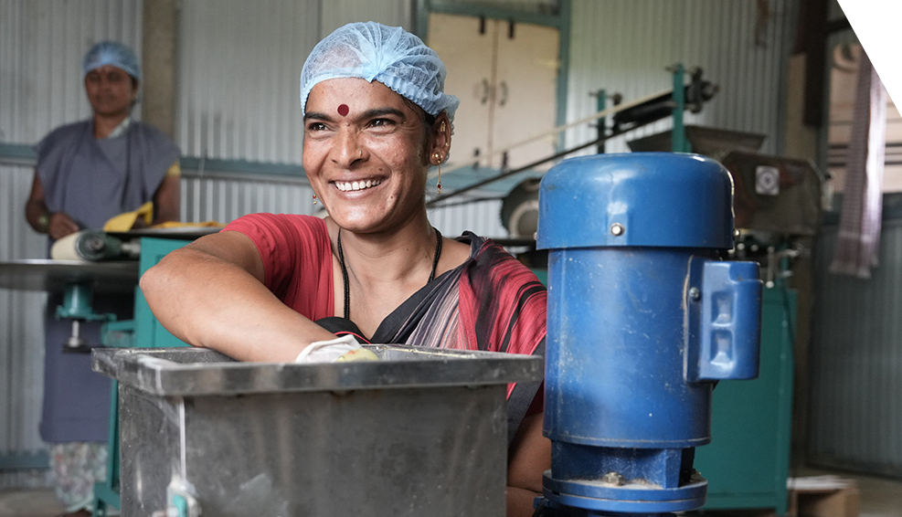 A woman from India beams with laughter as she uses a machine power by clean solar energy supllied by Selco.