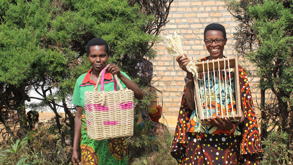 Two women holding woven handbag and garments smiling at the camera