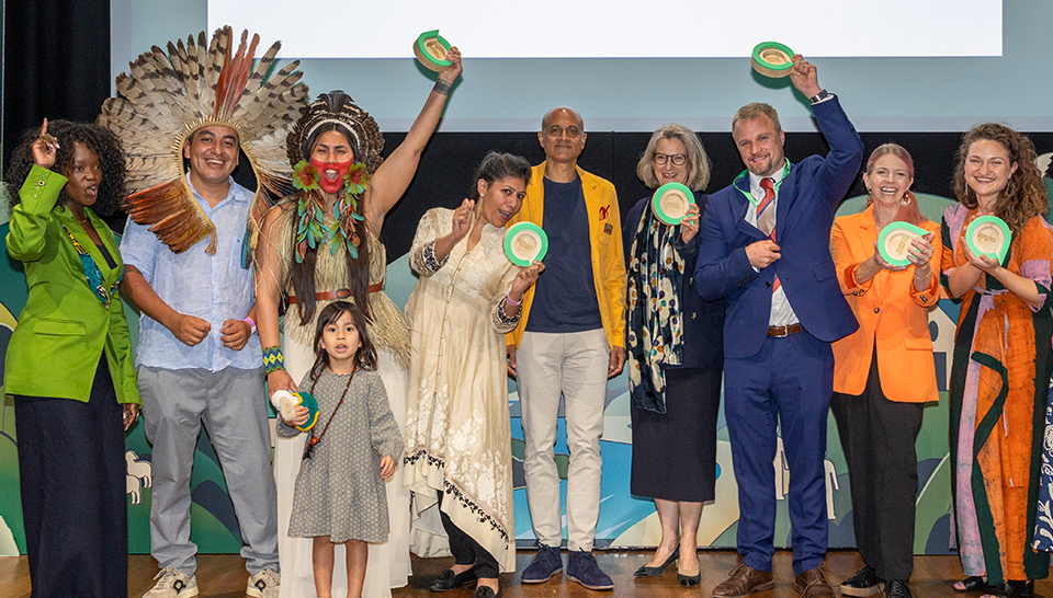 The 2026 Ashden climate award winners are stood on stage cheering.