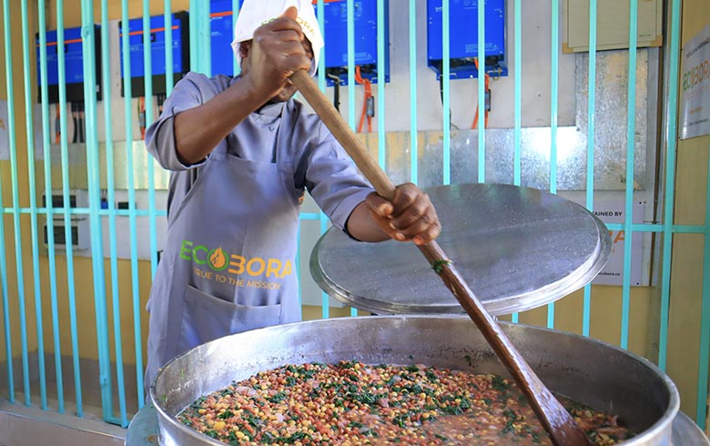 A school cook is making a huge pot on food for pupils using a clean cooking stove from Eco Bora
